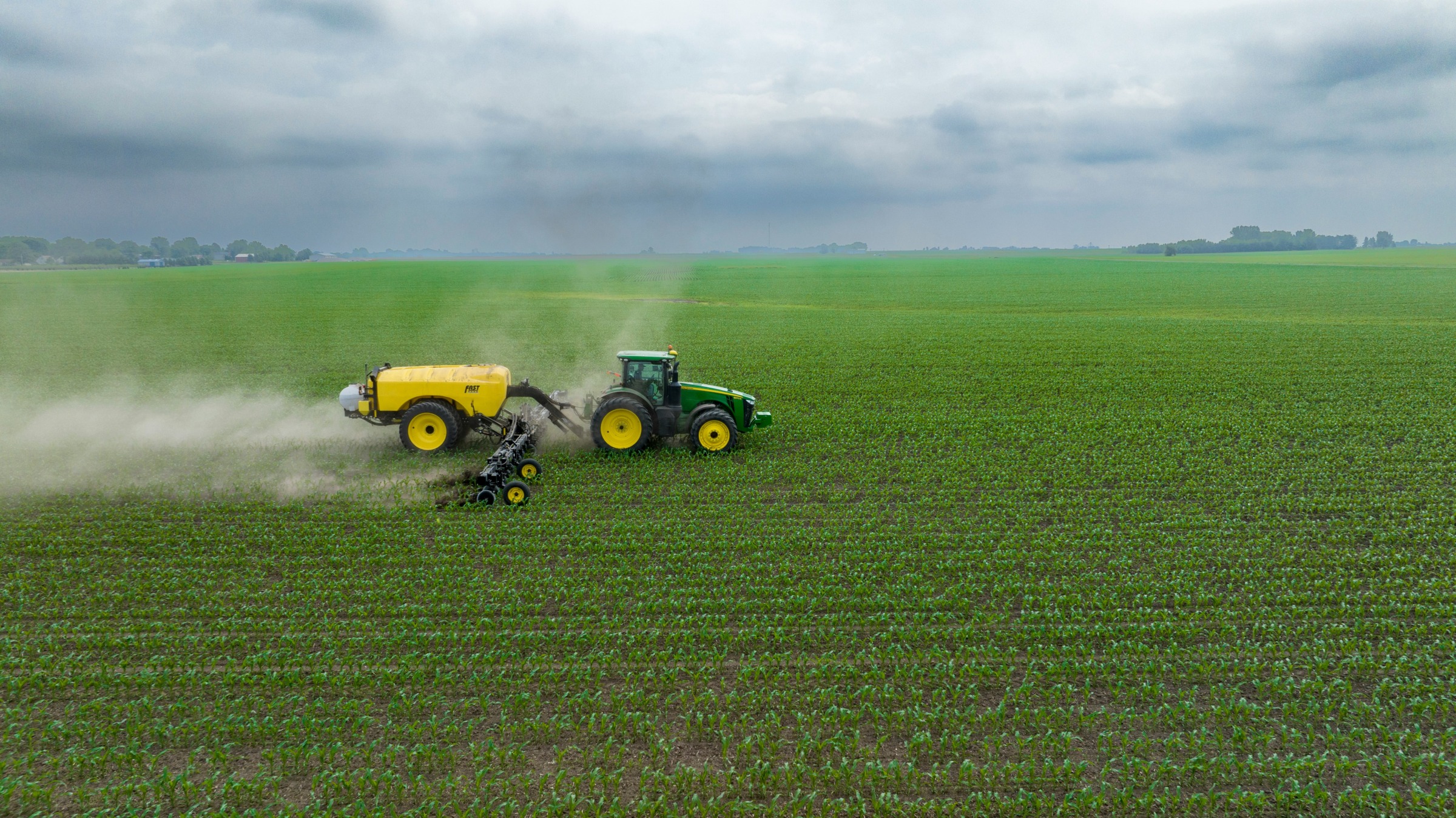 Green tractor spreading nitrogen on a field