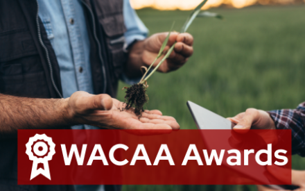 Image of two people's hands one examining a crop and the other holding a piece of paper. The text outlined in red WACAA Awards overlays the image.