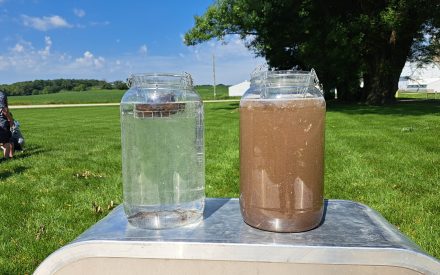 Visual of a slake test, two jars of water one is clear and one is filled with broken soil particles