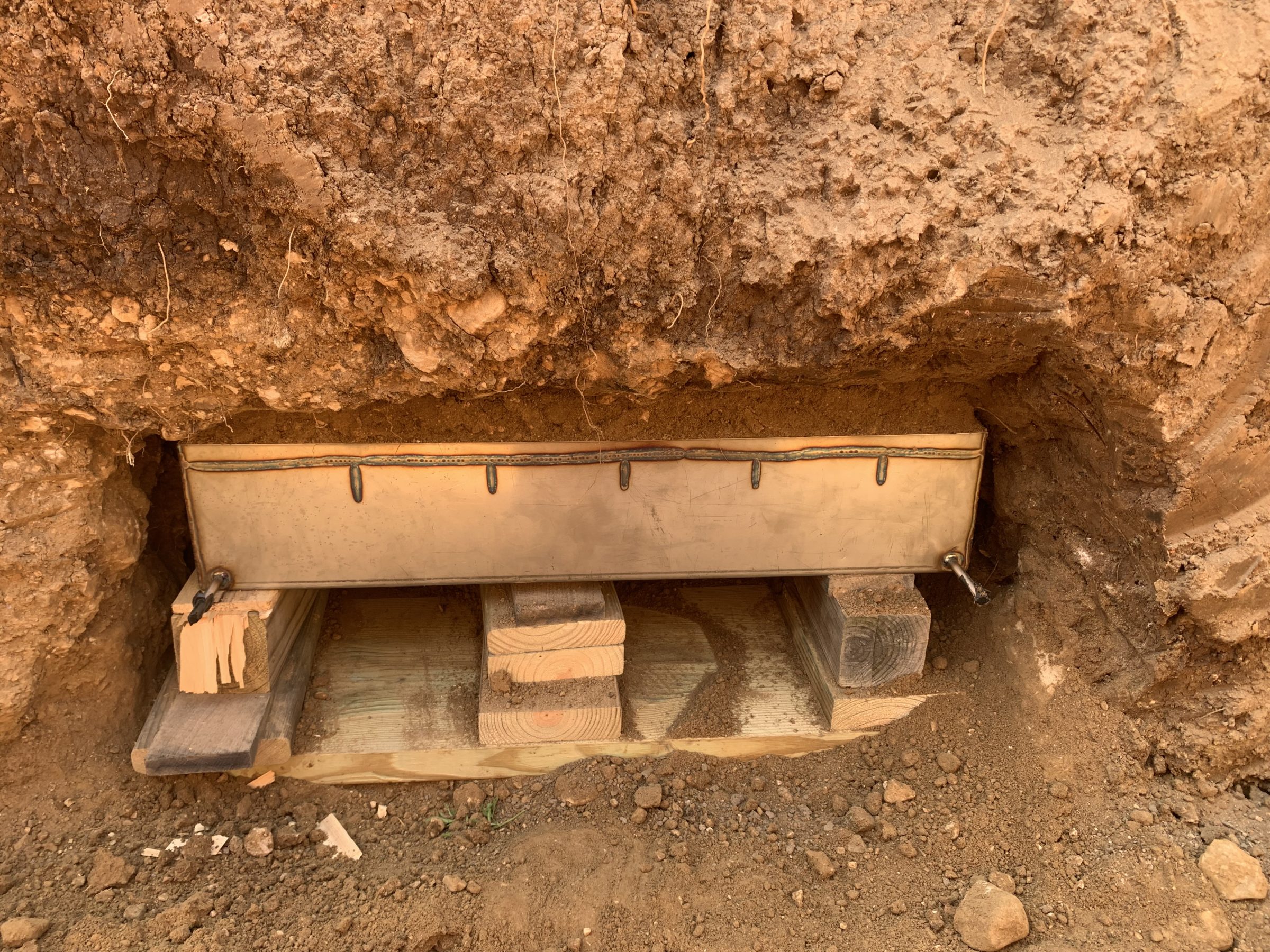 Soil erosion monitoring device installed in excavated trench showing soil layers and wooden frame